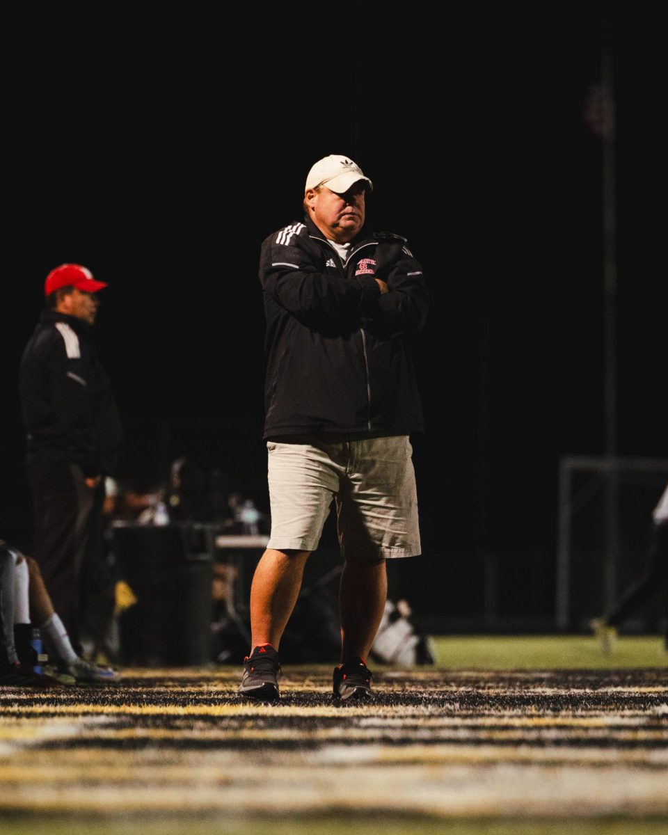 Head coach Troy Adams stands on the sidelines during Central’s game against Metea Valley on Oct. 1. The Redhawks lost 2-1 in double overtime.