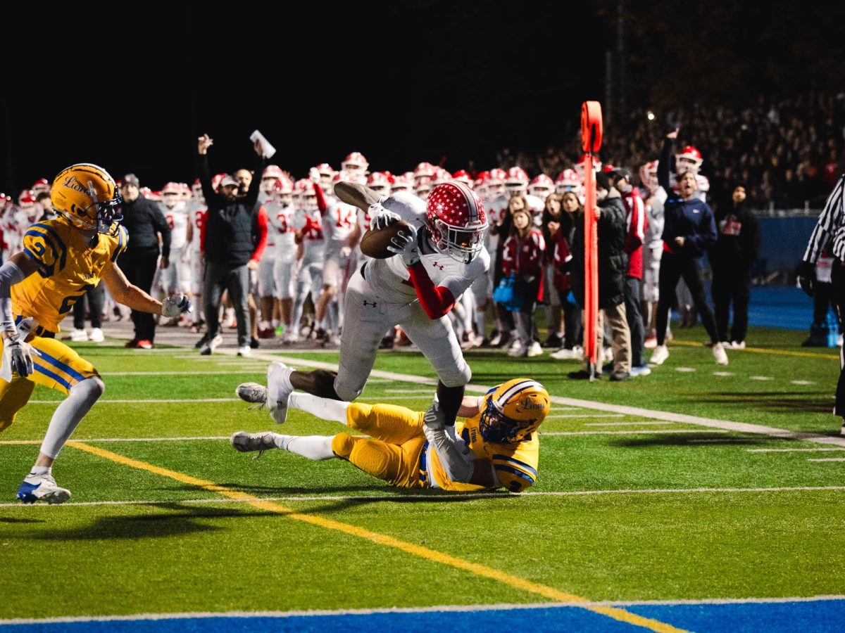 Naperville Central head coach Mike Ulreich celebrates in the background as senior DeShaun Williams surges forwards to convert on a fourth down in a game against Lyons Township on Nov. 15. The first down allowed quarterback Sebastian Hayes to rush for a touchdown on a following play.